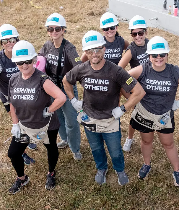 A group of volunteers wearing shirts that say "serving others"