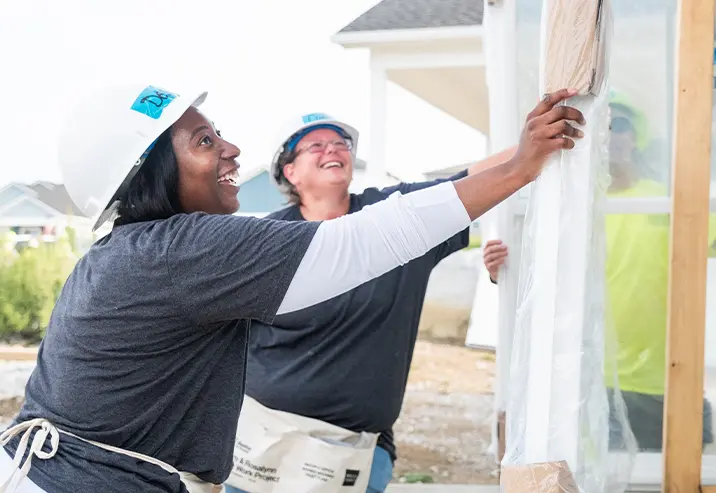 Two volunteers working on the windows of a home