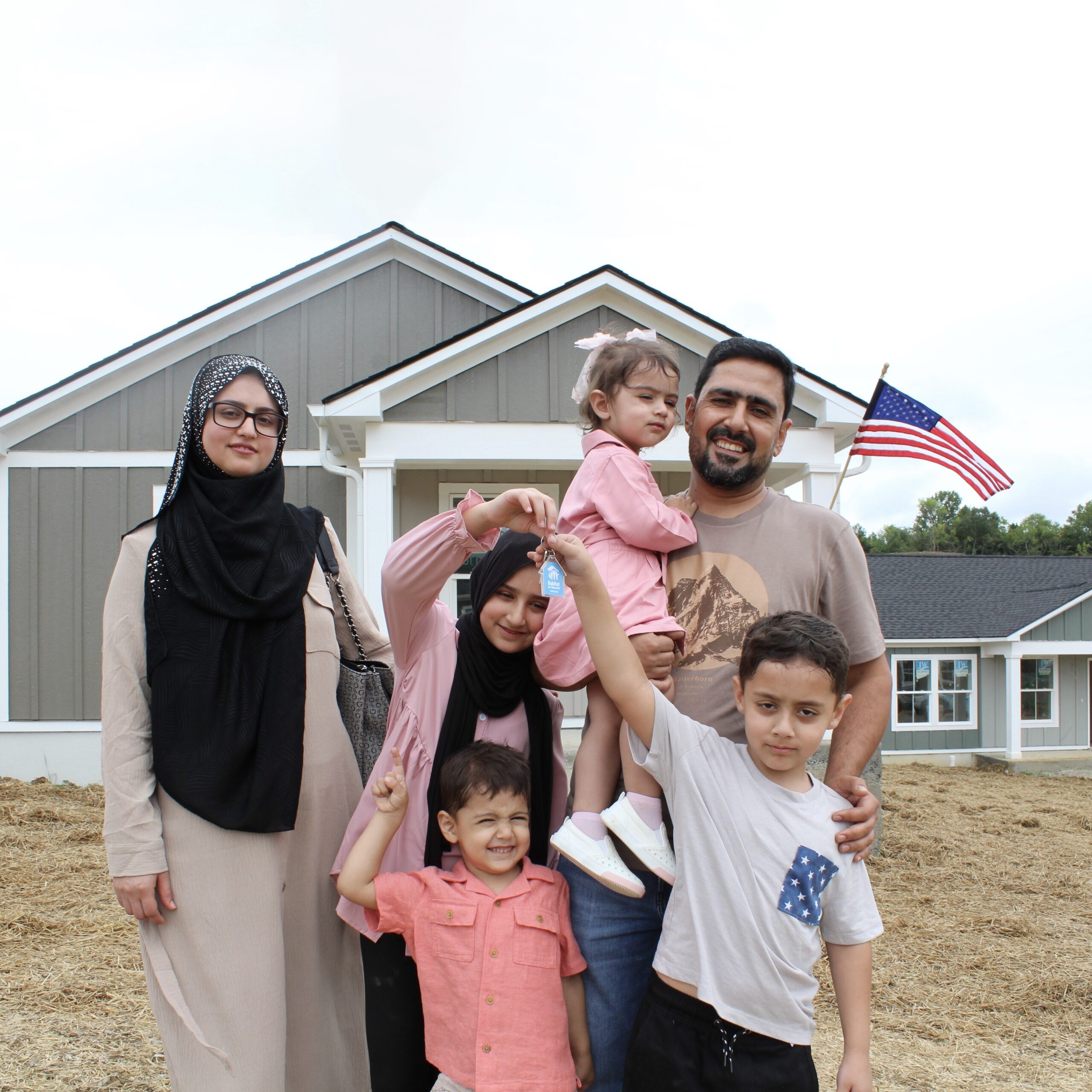 A smiling family in front of their new Habitat for Humanity house